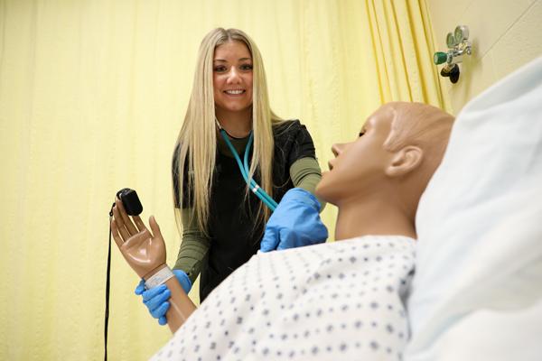 一个女学生在给人体模特量脉搏.